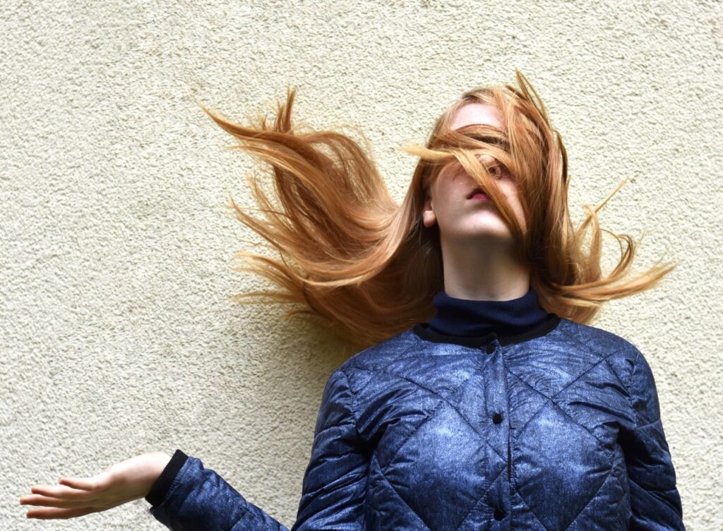 pexels photo 206336 Stylish blonde woman with hair flipping in a bold pose against a textured wall.